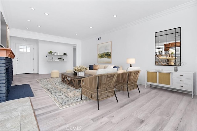 living room featuring crown molding, light hardwood / wood-style floors, and a brick fireplace