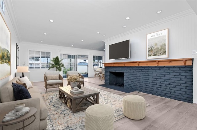 living room with a brick fireplace, light hardwood / wood-style floors, and crown molding