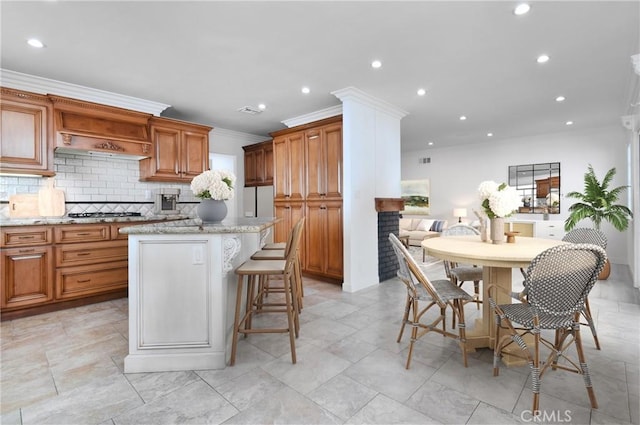 kitchen with light stone counters, a kitchen breakfast bar, a center island, and decorative backsplash