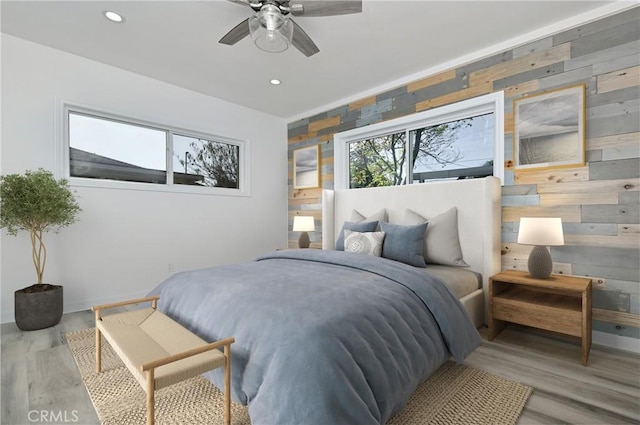 bedroom featuring wood walls, light hardwood / wood-style floors, and ceiling fan