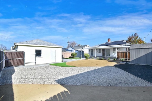 rear view of property featuring solar panels and a shed