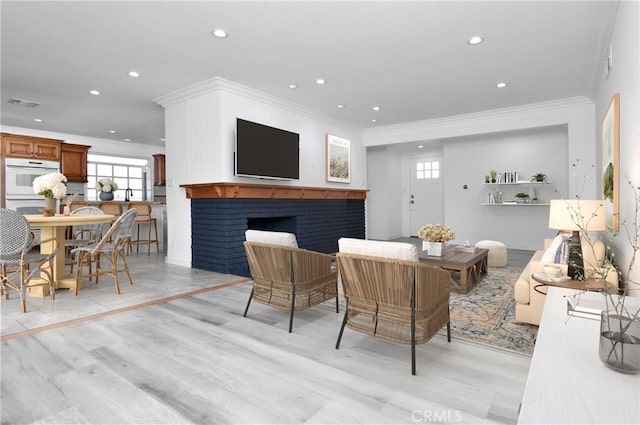 living room featuring crown molding, light wood-type flooring, and a fireplace