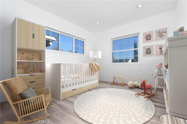 bedroom featuring light hardwood / wood-style flooring and a crib