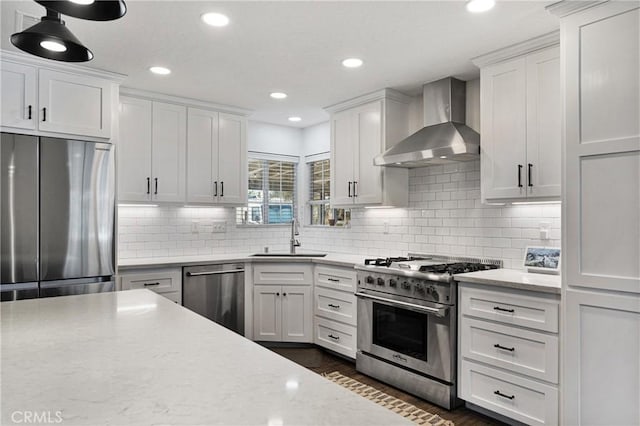 kitchen with stainless steel appliances, wall chimney exhaust hood, white cabinetry, and sink