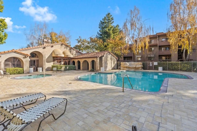 view of swimming pool featuring a hot tub and a patio area