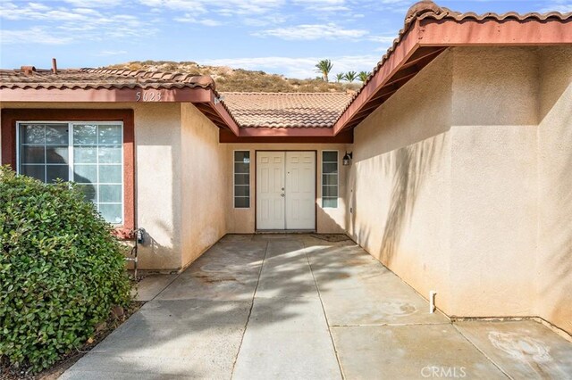 view of exterior entry with a patio