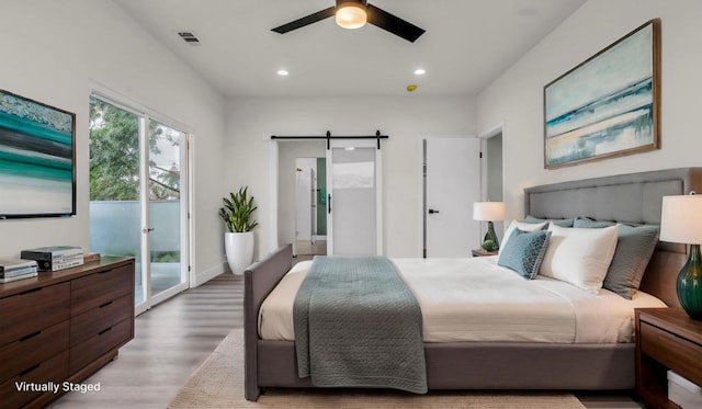 bedroom with ceiling fan, a barn door, access to exterior, and hardwood / wood-style floors