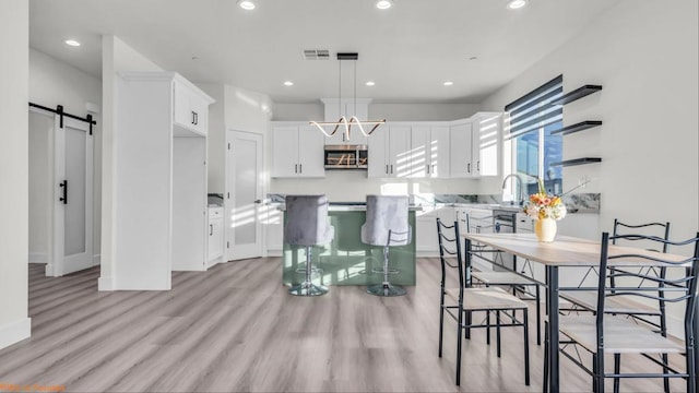 dining room featuring a barn door, sink, and light hardwood / wood-style flooring