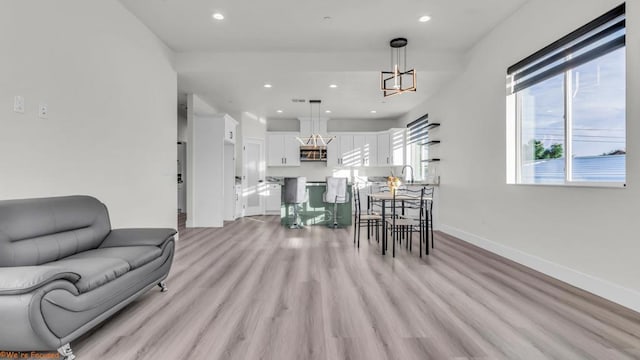 living room with light wood-type flooring, an inviting chandelier, and sink