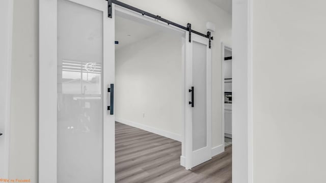 hall featuring a barn door and light hardwood / wood-style flooring