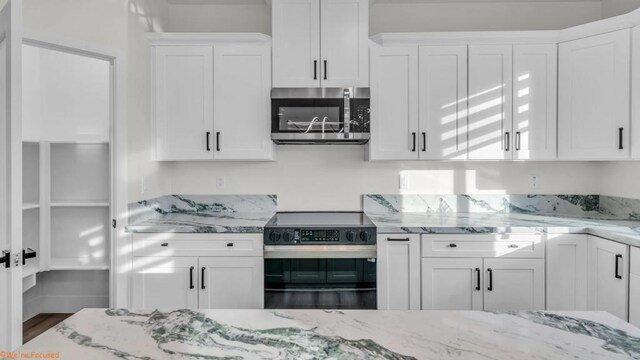 kitchen with appliances with stainless steel finishes, white cabinets, and light stone countertops