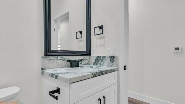 bathroom featuring toilet, vanity, and hardwood / wood-style flooring