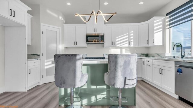 kitchen with white cabinetry, light stone counters, hanging light fixtures, and stainless steel appliances