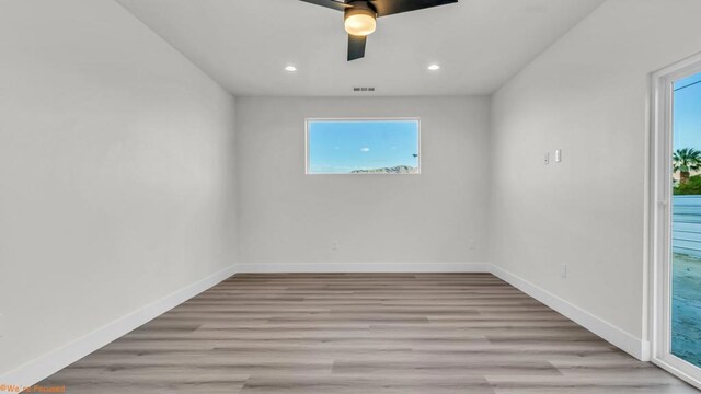 empty room featuring ceiling fan, plenty of natural light, and light hardwood / wood-style flooring