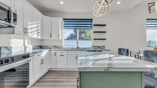 kitchen with hanging light fixtures, white cabinets, and oven