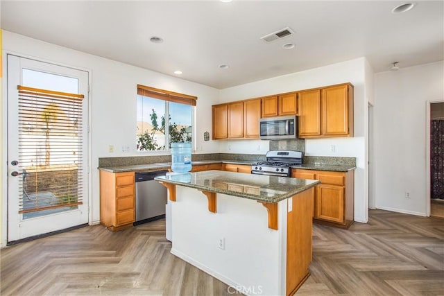 kitchen with a wealth of natural light, appliances with stainless steel finishes, a breakfast bar area, and a center island