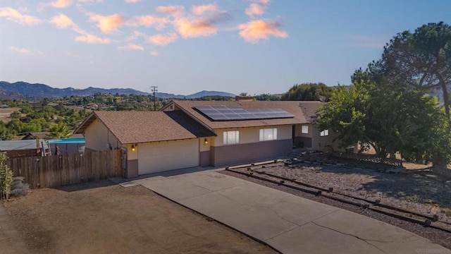 view of front of home with a mountain view, a garage, and solar panels