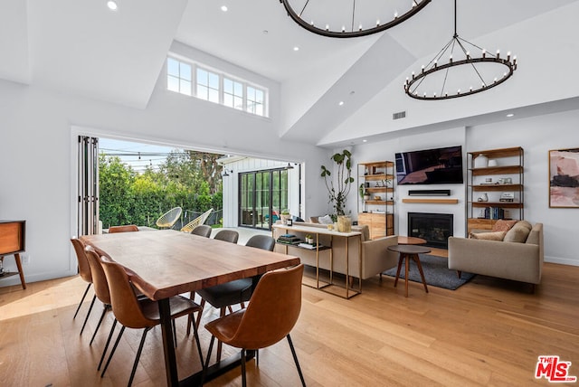 dining area featuring a towering ceiling and light wood-type flooring