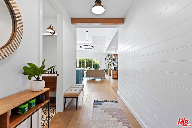 hallway featuring beam ceiling and light hardwood / wood-style floors