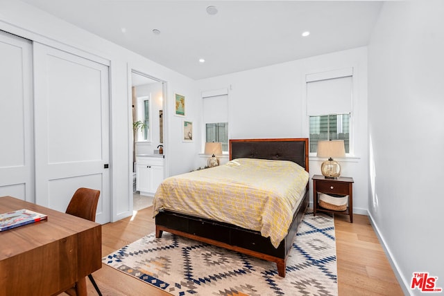 bedroom with a closet, connected bathroom, and light hardwood / wood-style flooring