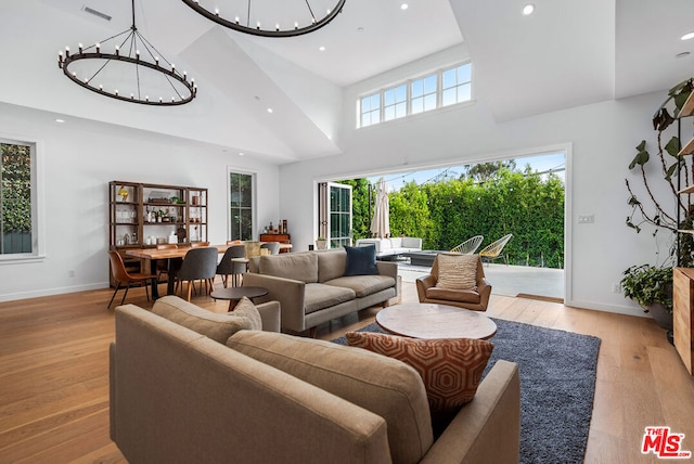 living room featuring a high ceiling, light hardwood / wood-style flooring, and a notable chandelier