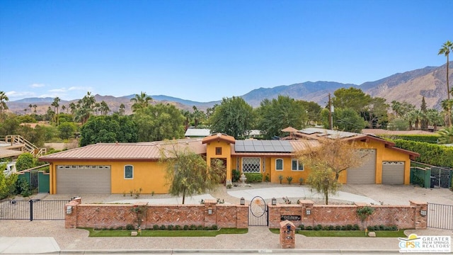 single story home with a mountain view, a garage, and solar panels