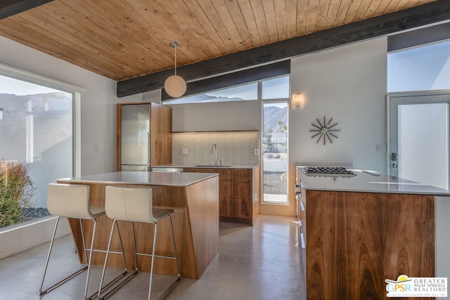 kitchen featuring tasteful backsplash, decorative light fixtures, wooden ceiling, a kitchen island, and beam ceiling