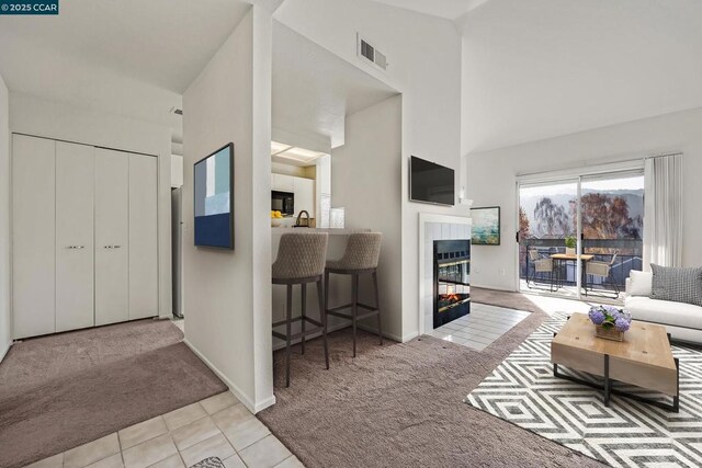 carpeted living room with high vaulted ceiling, a tile fireplace, and sink