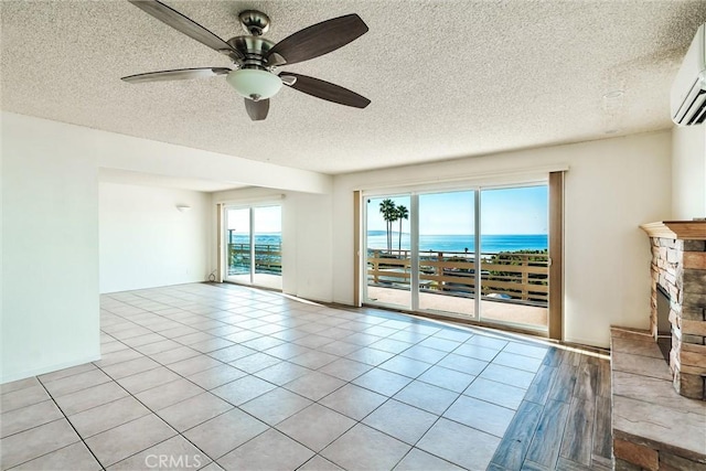 empty room featuring ceiling fan, a water view, plenty of natural light, and a fireplace