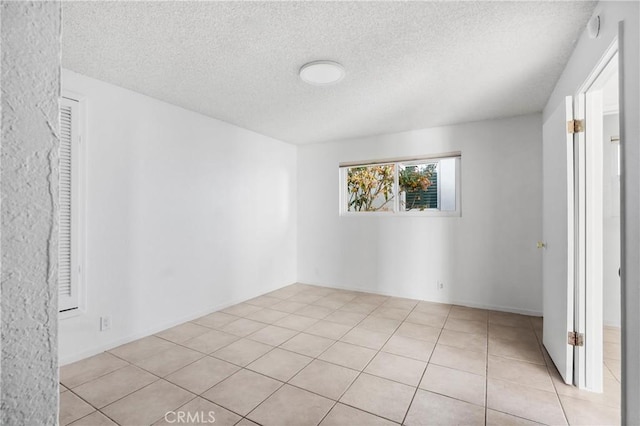 empty room with a textured ceiling and light tile patterned flooring