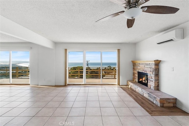 unfurnished living room featuring a wall unit AC, ceiling fan, a water view, and light tile patterned flooring