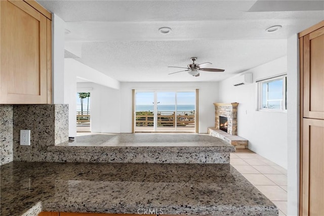 unfurnished living room featuring a wall unit AC, ceiling fan, a healthy amount of sunlight, and a textured ceiling