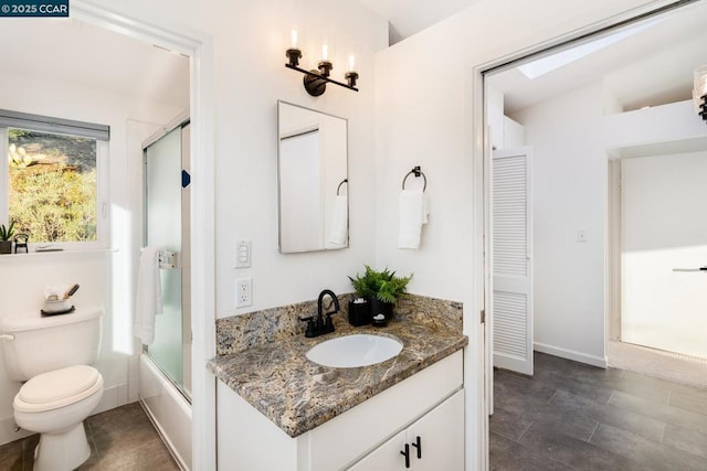 full bathroom featuring toilet, vanity, and bath / shower combo with glass door