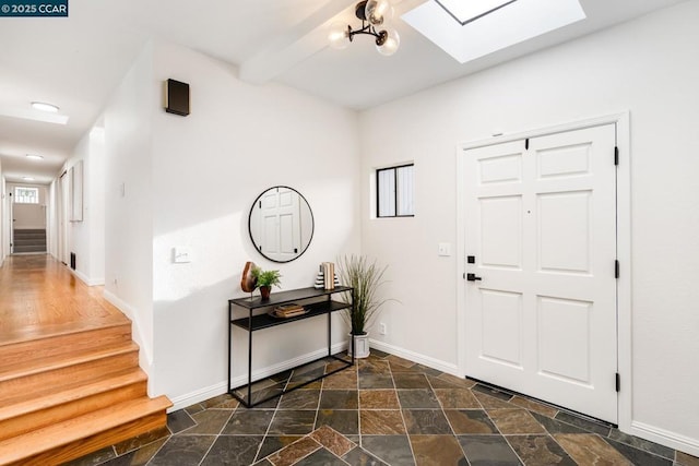 foyer entrance with a skylight and a chandelier