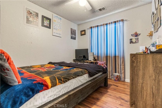 bedroom with ceiling fan, a textured ceiling, and hardwood / wood-style flooring