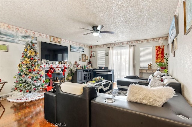 living room with ceiling fan, a textured ceiling, and wood-type flooring