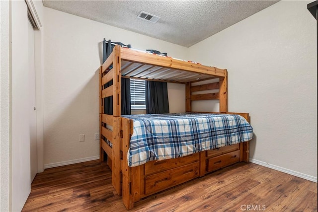 bedroom with a textured ceiling and hardwood / wood-style flooring