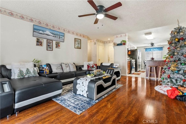 living room featuring ceiling fan, a textured ceiling, and hardwood / wood-style floors