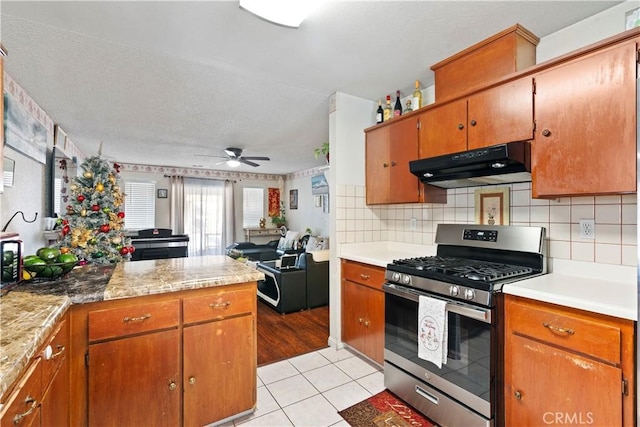 kitchen with stainless steel gas range, light tile patterned floors, tasteful backsplash, and ceiling fan