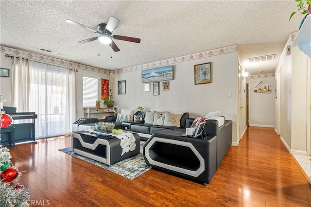 living room with a textured ceiling, ceiling fan, and hardwood / wood-style flooring