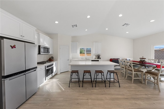 kitchen with white cabinetry, a kitchen breakfast bar, stainless steel appliances, and a center island