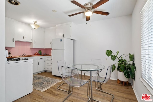 kitchen with white cabinetry, backsplash, white appliances, and light wood-type flooring