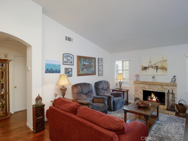 living room featuring vaulted ceiling, a fireplace, and hardwood / wood-style floors