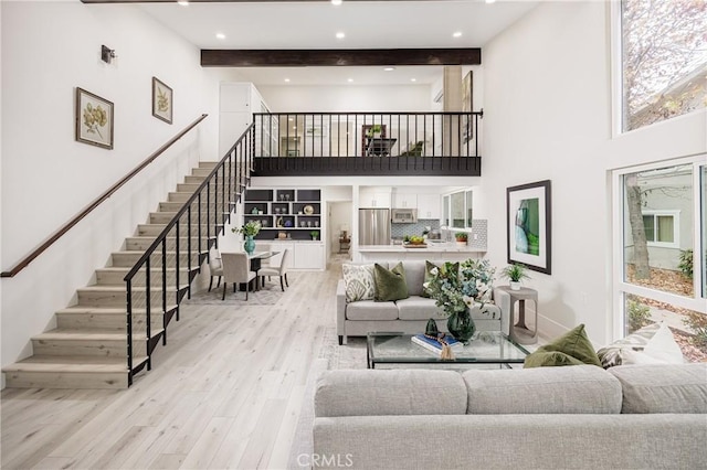 living room featuring light hardwood / wood-style floors, a high ceiling, and beamed ceiling