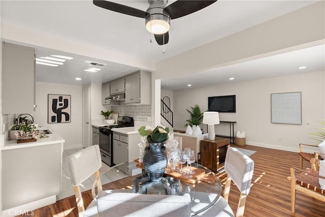 dining space with ceiling fan, sink, and light hardwood / wood-style flooring