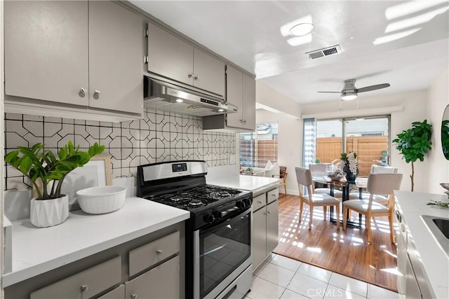 kitchen featuring decorative backsplash, light tile patterned flooring, ceiling fan, stainless steel range with gas cooktop, and gray cabinetry