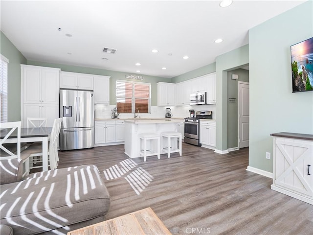 kitchen with a kitchen breakfast bar, white cabinetry, appliances with stainless steel finishes, and a kitchen island