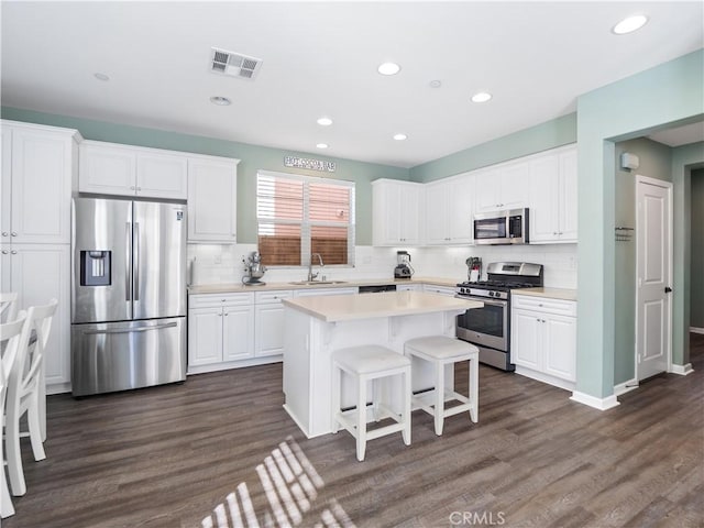 kitchen featuring a center island, sink, appliances with stainless steel finishes, white cabinets, and dark hardwood / wood-style flooring