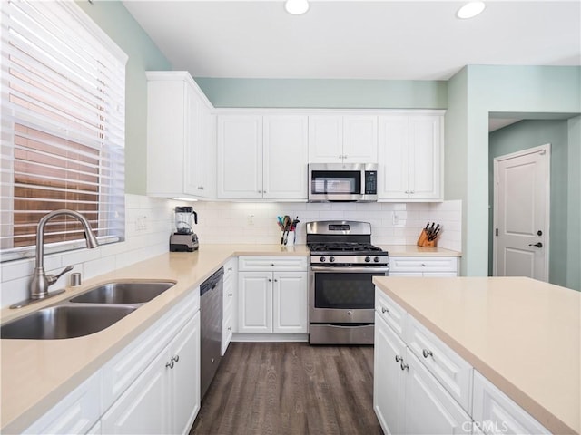 kitchen featuring white cabinetry, appliances with stainless steel finishes, dark hardwood / wood-style floors, backsplash, and sink