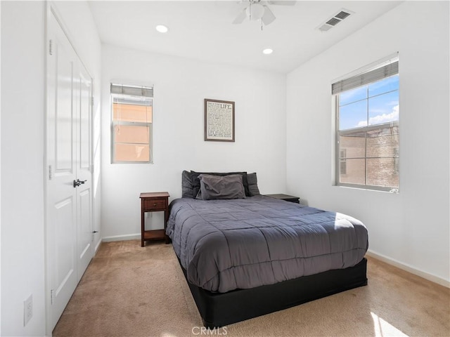 bedroom with ceiling fan, light colored carpet, and a closet